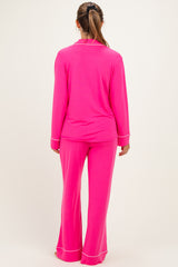woman wearing a bright pink maternity pajama set with long sleeves and flared pants, view from the back