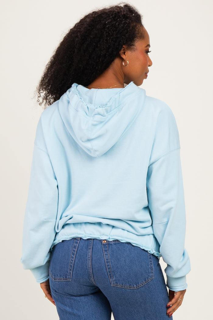 woman wearing a light blue hooded sweatshirt with a relaxed fit and ruffled hem, seen from the back