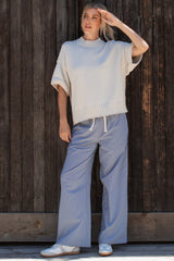 woman wearing a neutral oversized knit top and light blue checked wide-leg pants, styled with white sneakers
