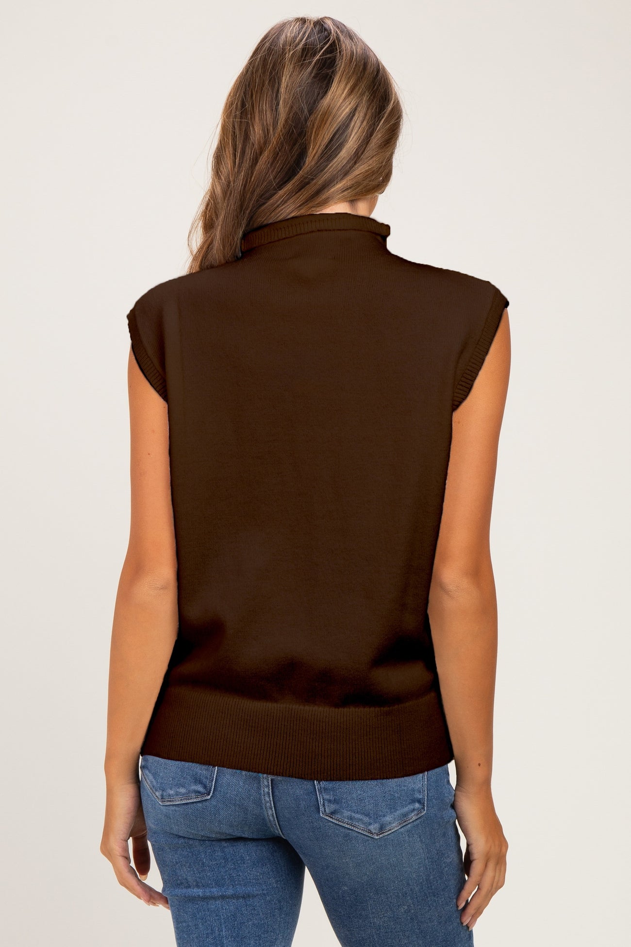 woman wearing a brown sleeveless maternity top, showing her back, paired with blue jeans