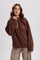 woman wearing a brown fleece pullover with a half-zip and light tan accents, paired with checkered pants