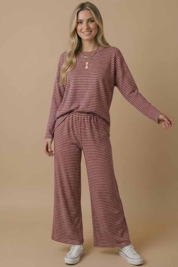 woman wearing a pink and white striped loungewear set with a relaxed fit top and wide-leg pants