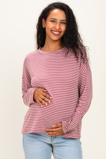 woman wearing a mauve and white striped maternity top and holding her baby bump