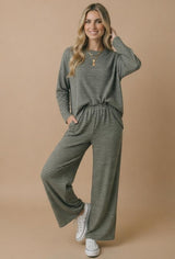 woman wearing a green and black striped long sleeve top and matching wide-leg pants with pockets and white sneakers