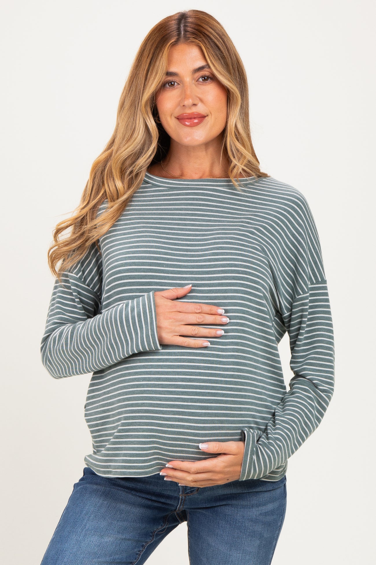 woman wearing a green and white striped maternity top and holding her baby bump