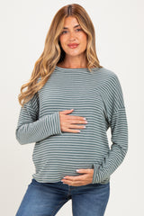 woman wearing a green and white striped maternity top and holding her baby bump