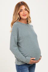 woman wearing a green and white striped maternity top and holding her baby bump