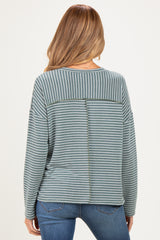 woman wearing a striped green maternity sweatshirt with an open back detail, styled with blue jeans