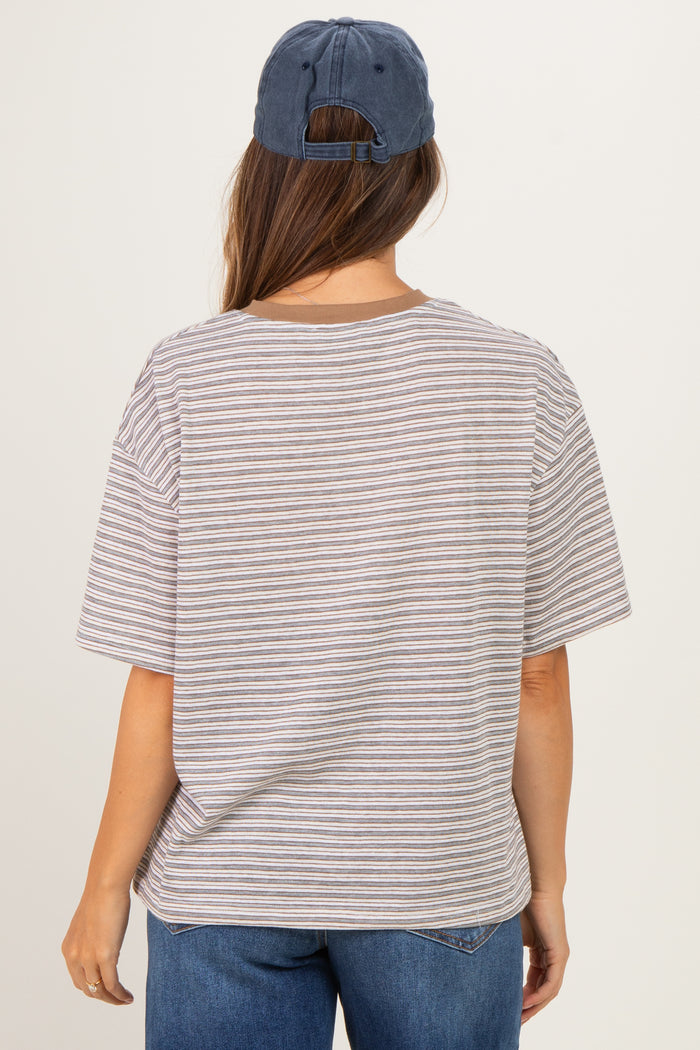 woman wearing a striped gray and white oversized maternity t-shirt and a blue baseball cap