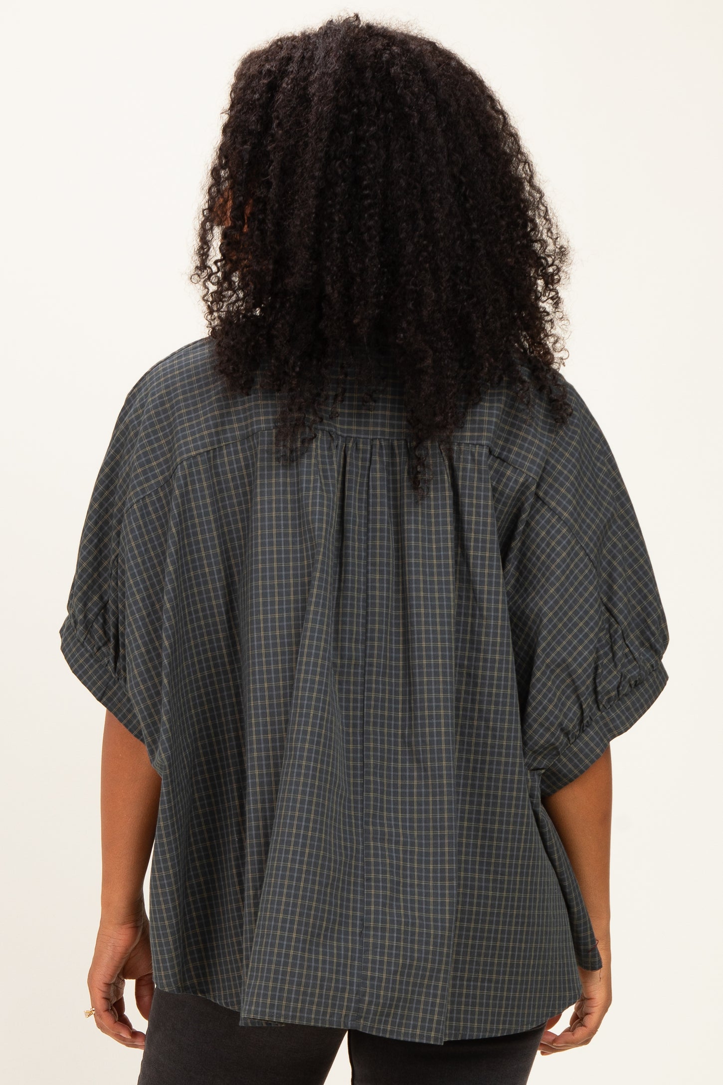 woman wearing a dark green plaid oversized blouse with puff sleeves, shown from the back