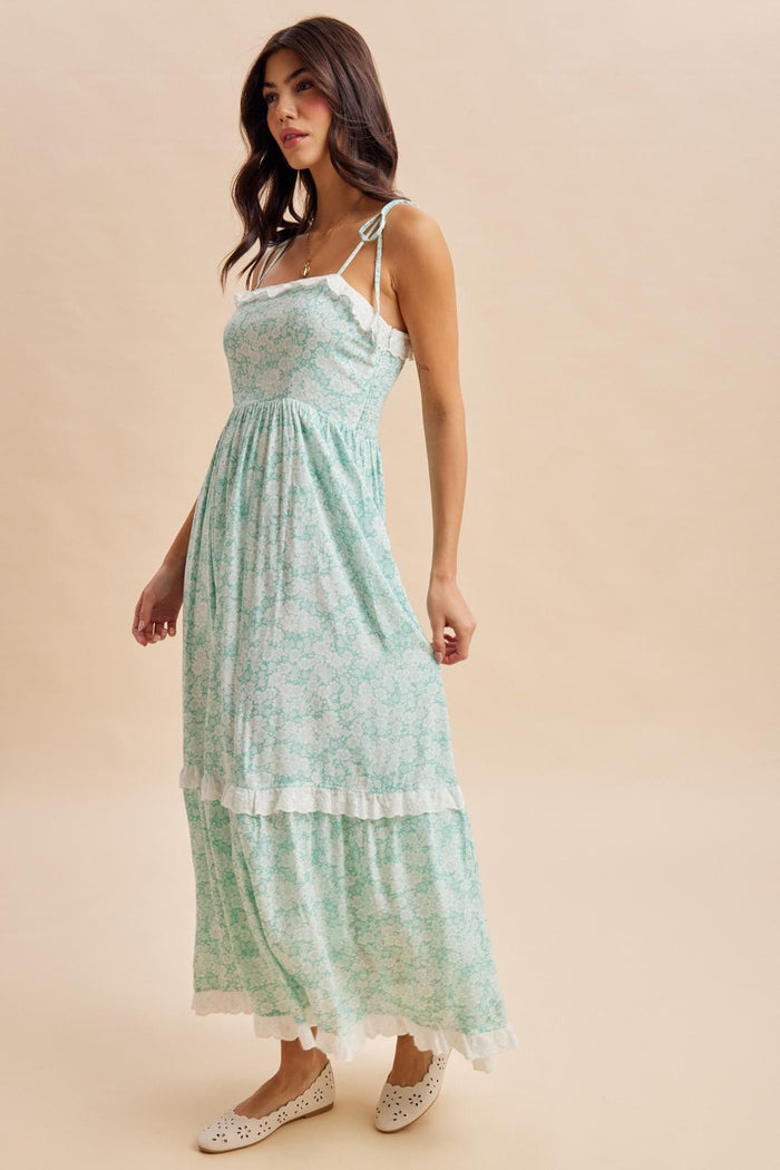 woman wearing a mint green floral maxi dress with lace trim and adjustable straps