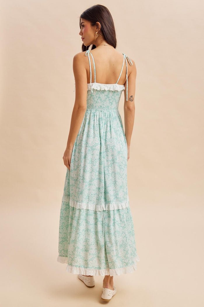woman wearing a mint green floral maxi dress with a smocked bodice and ruffled hem, facing away from the camera