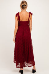 woman wearing a burgundy lace maternity dress with tie straps and a flowing maxi skirt, showing a baby bump from the back