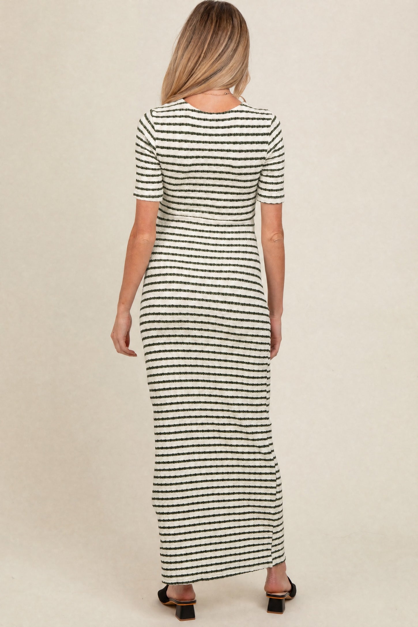 woman wearing a black and white striped maternity maxi dress, showing a form-fitting style from the back