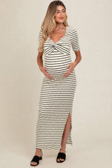 woman wearing a black and white striped maternity dress with a twist front and side slit, showing her baby bump