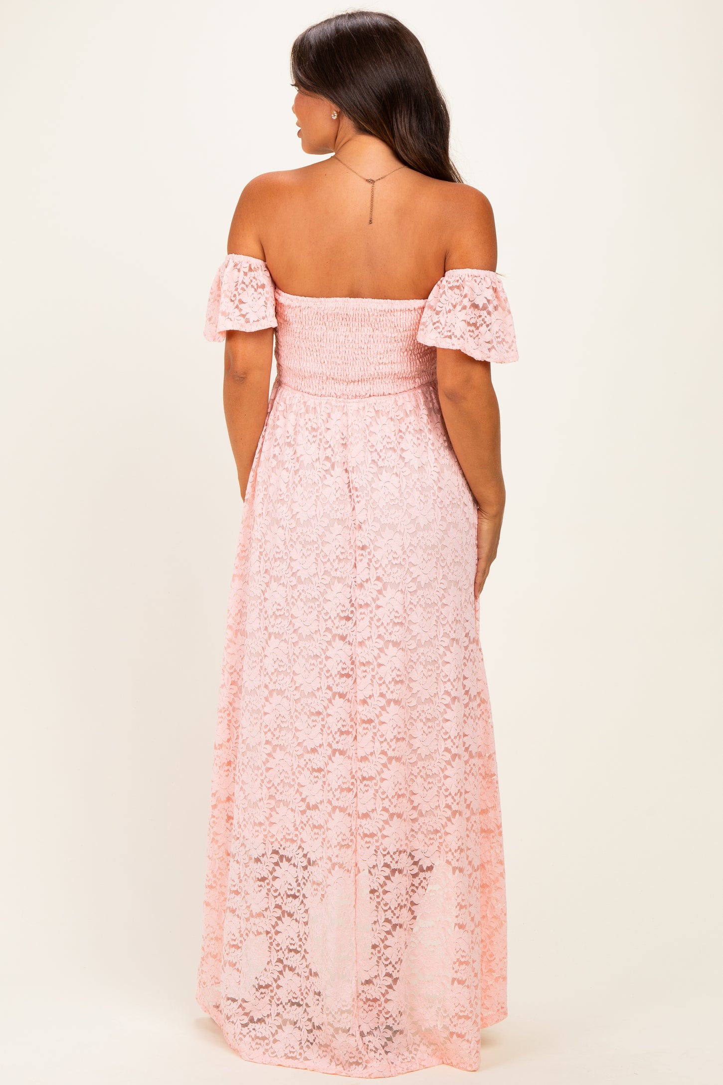 woman wearing a pink lace off-the-shoulder maternity maxi dress, showing a flowy and elegant back view