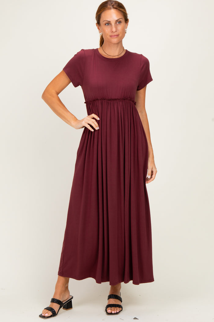 woman wearing a burgundy short sleeve maxi dress with a fitted waist and flowing skirt