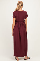 woman wearing a burgundy short sleeve maxi dress with an elastic waist detail, shown from the back