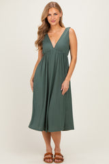 woman wearing a dark green pleated midi dress with a v-neckline and flared skirt