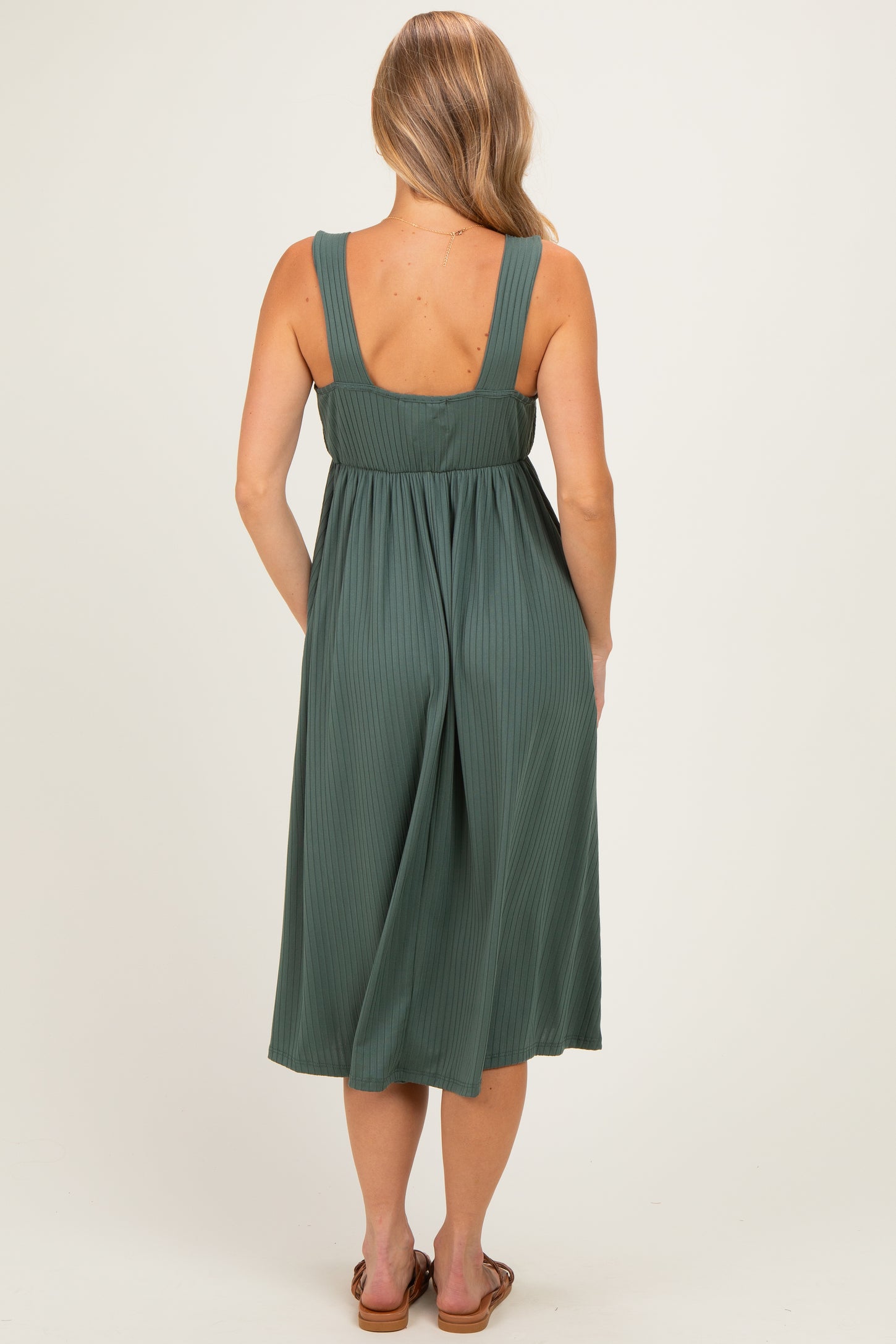 woman wearing a green pleated midi dress with wide straps, seen from the back