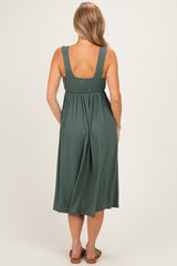 woman wearing a green pleated midi dress with wide straps, seen from the back