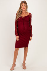 woman wearing a burgundy lace long sleeve maternity dress with a fitted silhouette and a sweetheart neckline, showcasing her baby bump