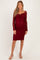 woman wearing a burgundy lace long sleeve maternity dress with a fitted silhouette and a sweetheart neckline, showcasing her baby bump