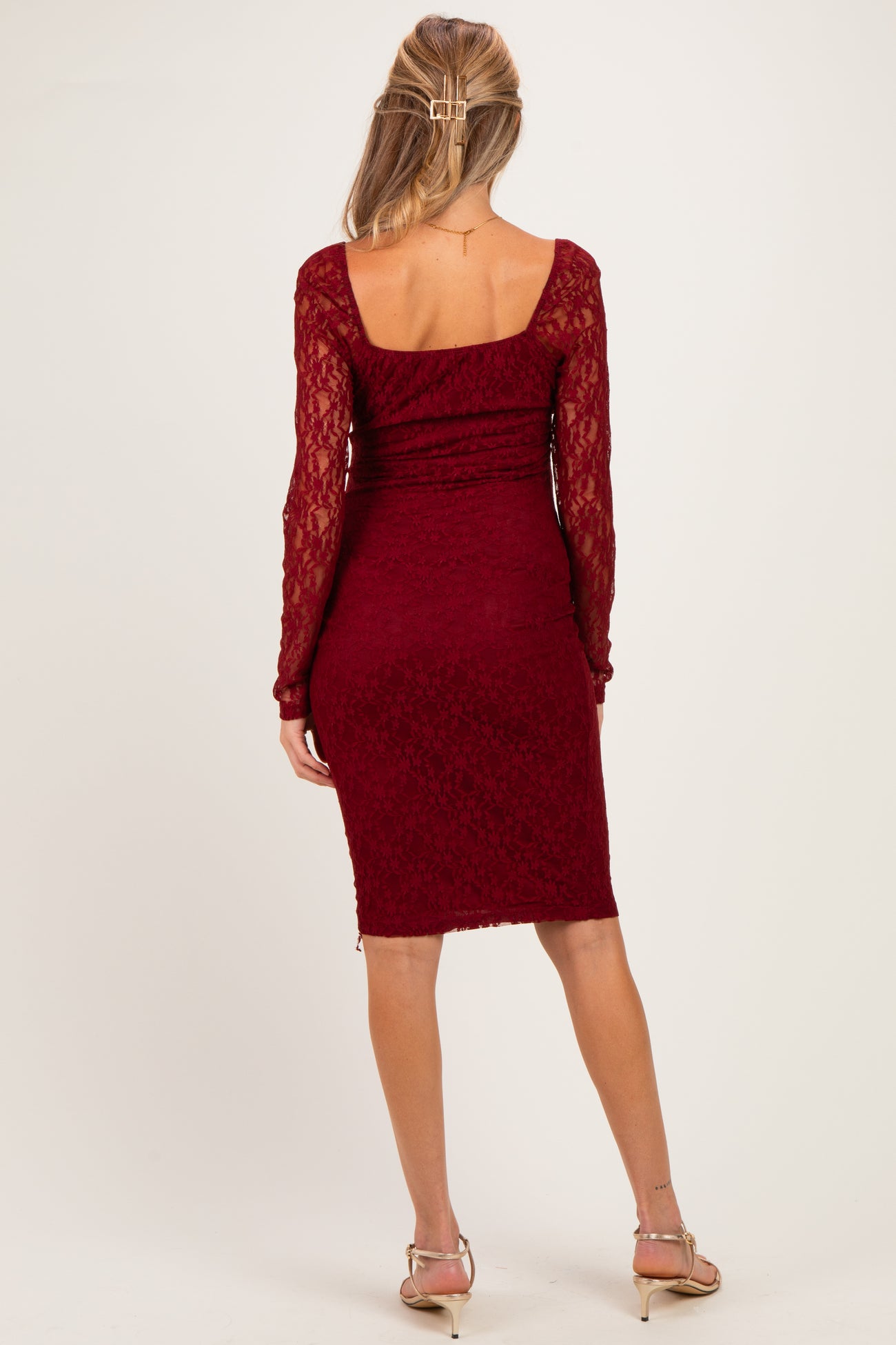 woman wearing a burgundy lace long sleeve maternity dress, viewed from the back