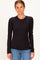woman wearing a black ribbed long sleeve top with a fitted style and round neckline, paired with blue jeans