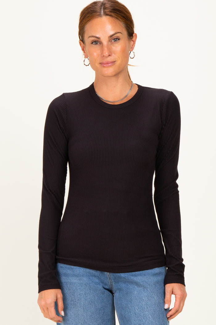 woman wearing a black ribbed long sleeve top with a fitted style and round neckline, paired with blue jeans