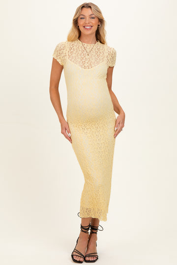 woman wearing a yellow lace maternity dress with short sleeves and a fitted silhouette, showcasing her baby bump