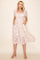 woman wearing a light pink floral midi dress with puff sleeves and pockets