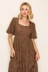 woman wearing a brown lace midi dress with short puff sleeves and a square neckline