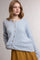 woman wearing a light blue button-up textured cardigan over a yellow polka dot skirt
