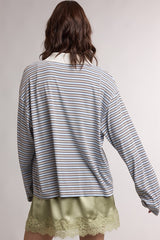 woman wearing a striped long sleeve top with a relaxed fit over a green satin camisole with lace trim