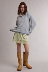woman wearing a striped long sleeve pullover shirt with an olive green mini skirt and brown knee-high boots