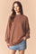woman wearing a brown oversized sweatshirt and a denim mini skirt