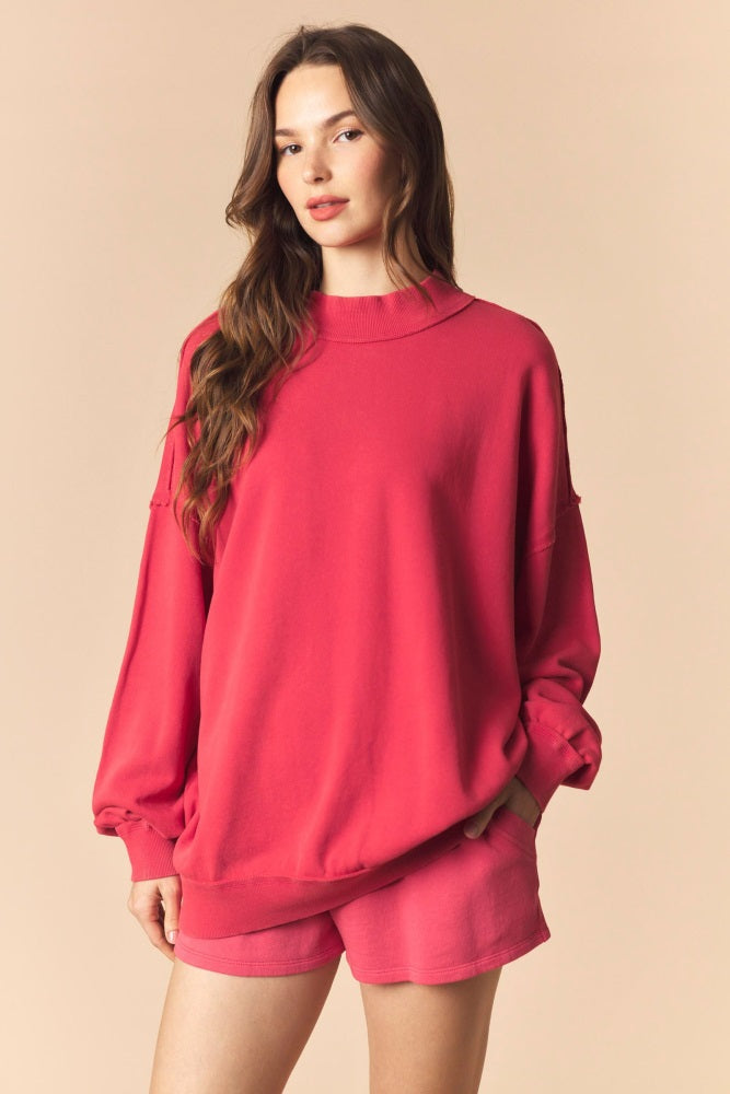 woman wearing a bright pink oversized sweatshirt with balloon sleeves and matching shorts