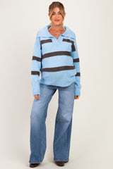 woman wearing a light blue and dark brown striped maternity sweater and blue flared jeans, showing a baby bump