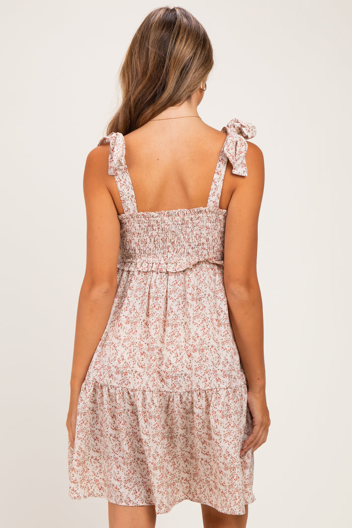 woman wearing a back view of a smocked floral maternity dress with bow straps