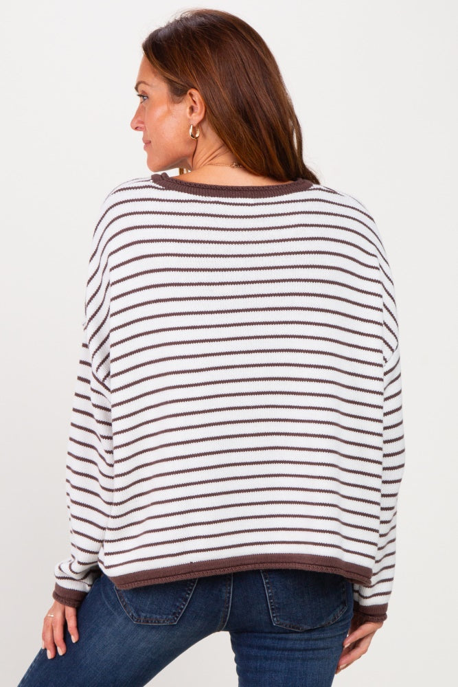 woman wearing a striped white and brown oversized sweater, showing the back view, paired with blue jeans