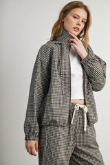 woman wearing a black and white checked zip-up jacket with a high collar and matching pants