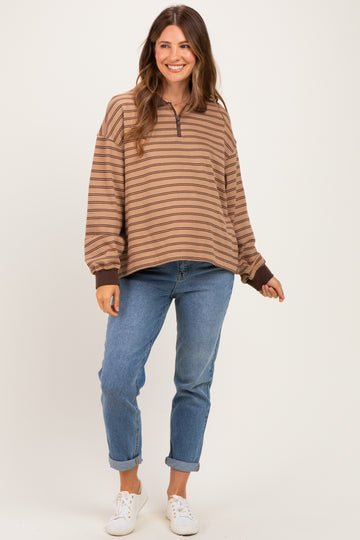 woman wearing a brown and beige striped maternity pullover with a half zip and casual jeans