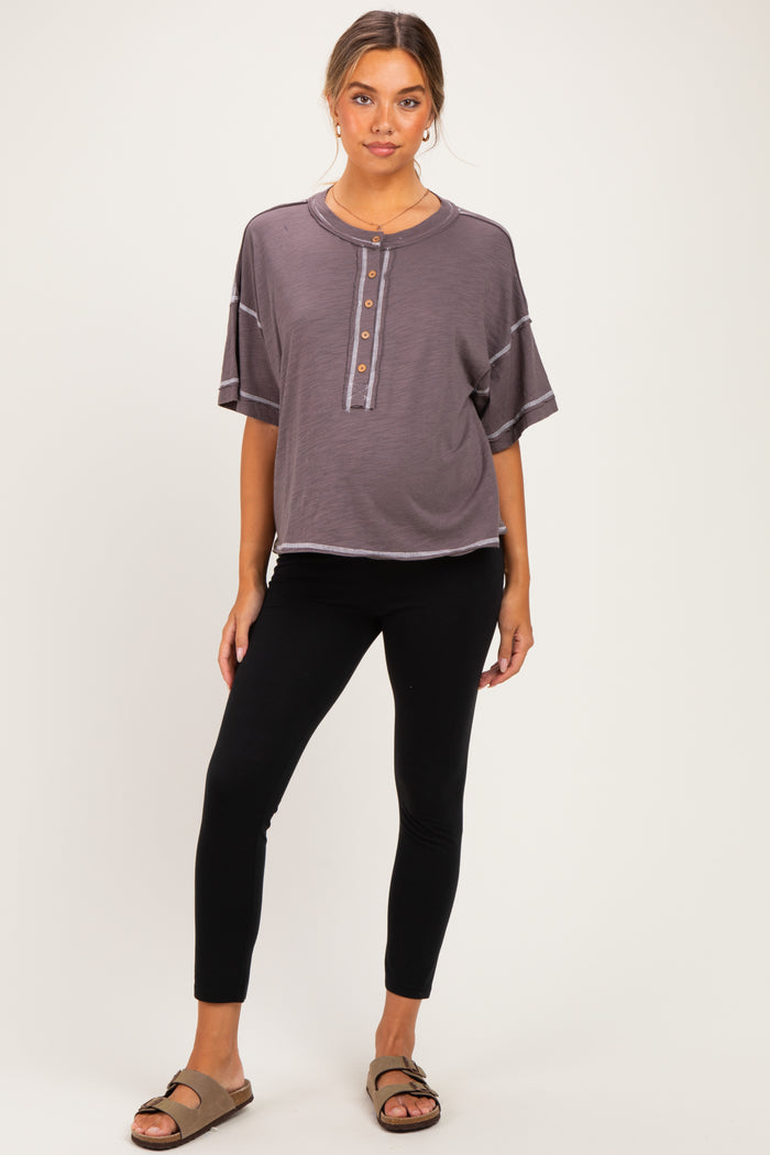 woman wearing a dark gray short sleeve maternity top with buttons and black maternity leggings