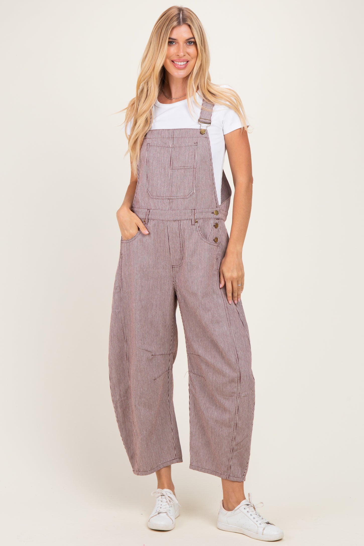 woman wearing striped red and white overalls with a white t-shirt underneath and white sneakers