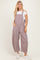 woman wearing striped red and white overalls with a white t-shirt underneath and white sneakers