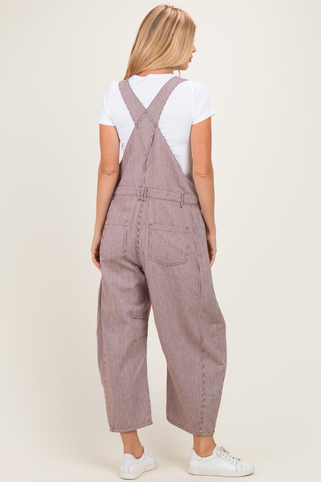 woman wearing striped overall pants with a white t-shirt, viewed from the back