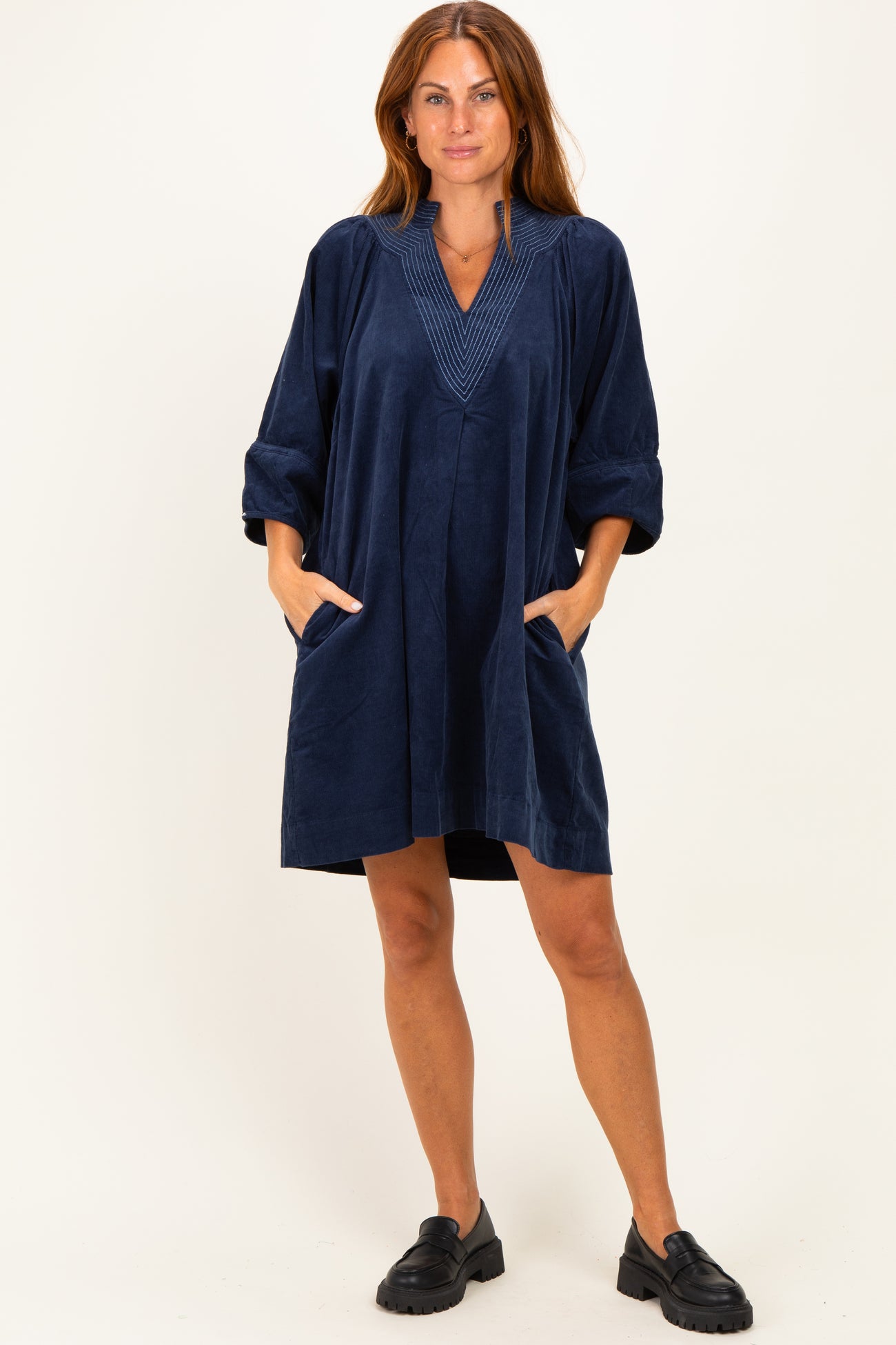 woman wearing a navy blue relaxed fit dress with a v-neckline and pockets