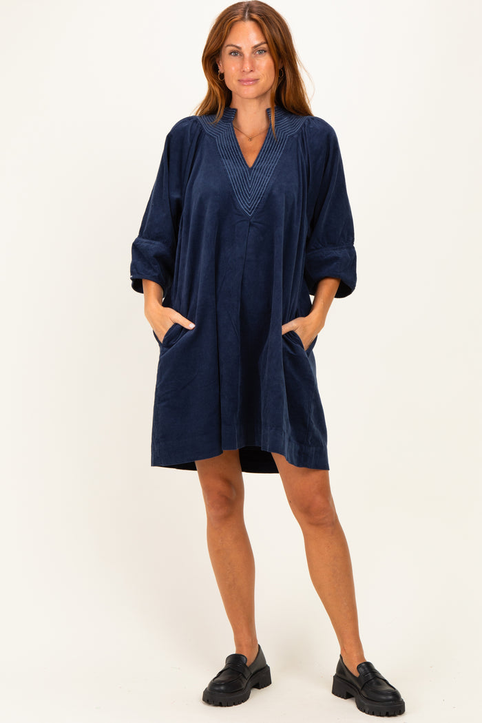 woman wearing a navy blue relaxed fit dress with a v-neckline and pockets