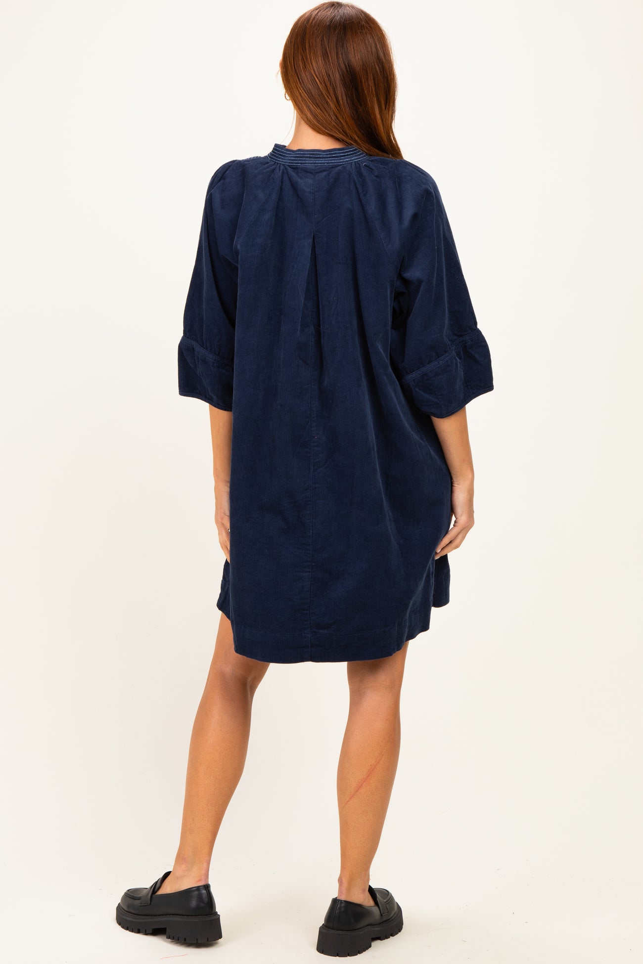 woman wearing a navy corduroy shirt dress with three-quarter sleeves and a relaxed fit, viewed from the back